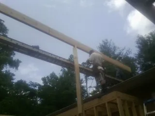 Carpenter setting a ridge beam over a new addition frame — Ice Dam Removal by Roofing Brothers in Livingston